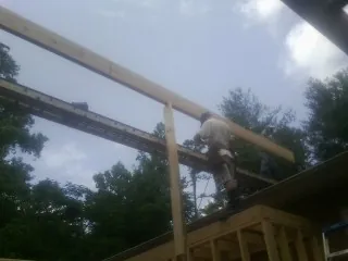 Carpenter setting a ridge beam over a new addition frame — Ice Dam Removal by Roofing Brothers in Joint Base Mdl