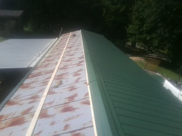 Old rusted panels beside newly installed green metal roofing — Wind Damage Roof Repair by Roofing Brothers in Joint Base Mdl
