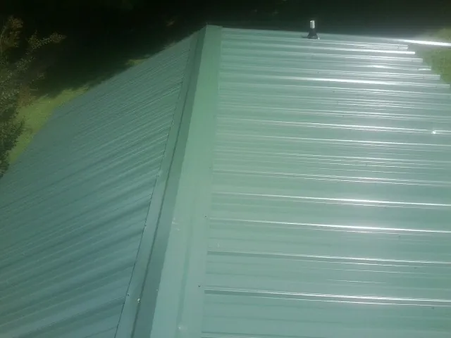 New green metal panels meeting at the ridge of a roof — Flat Roof Repair work by our crew in Joint Base Mdl