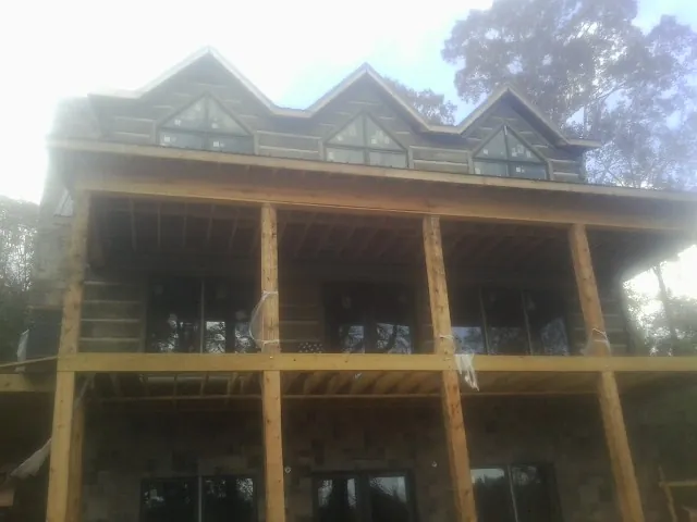 Dormers and porch framing on a large log home under construction — Roof Coating work by our crew in Joint Base Mdl