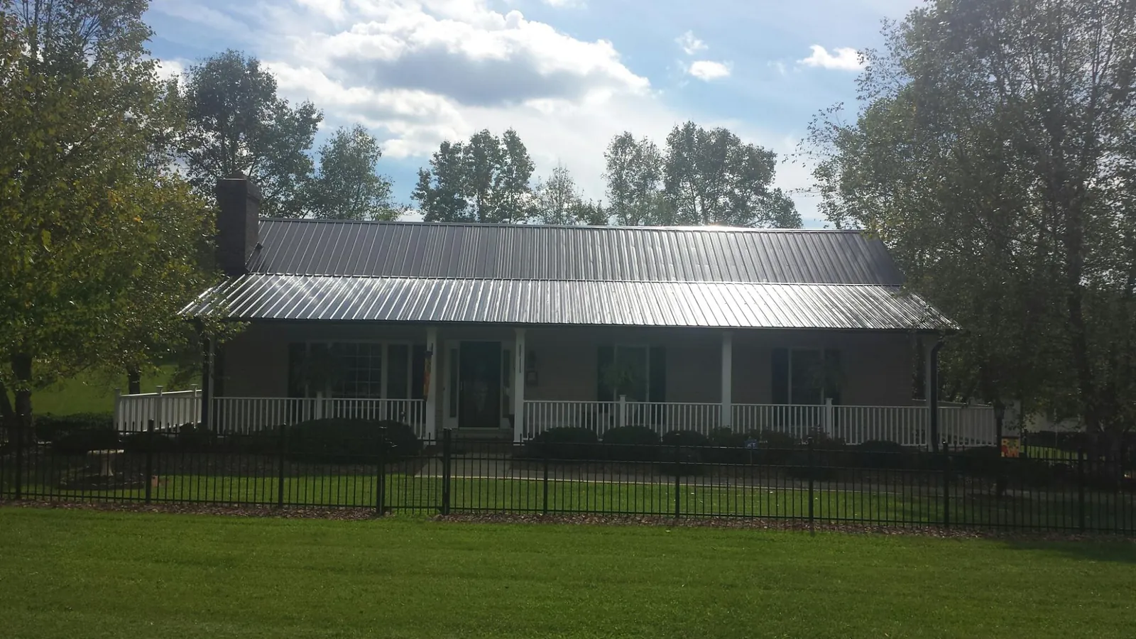 Gray metal roof on a brick ranch with a full width front porch — Gutter Guard Installation work by our crew in Joint Base Mdl