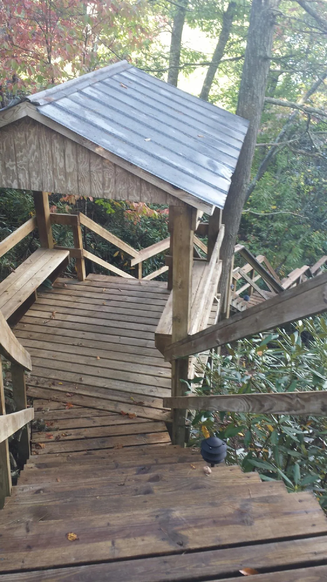 Metal roofed shelter over wooden steps on a wooded walkway — Skylight Repair & Installation work by our crew in Joint Base Mdl