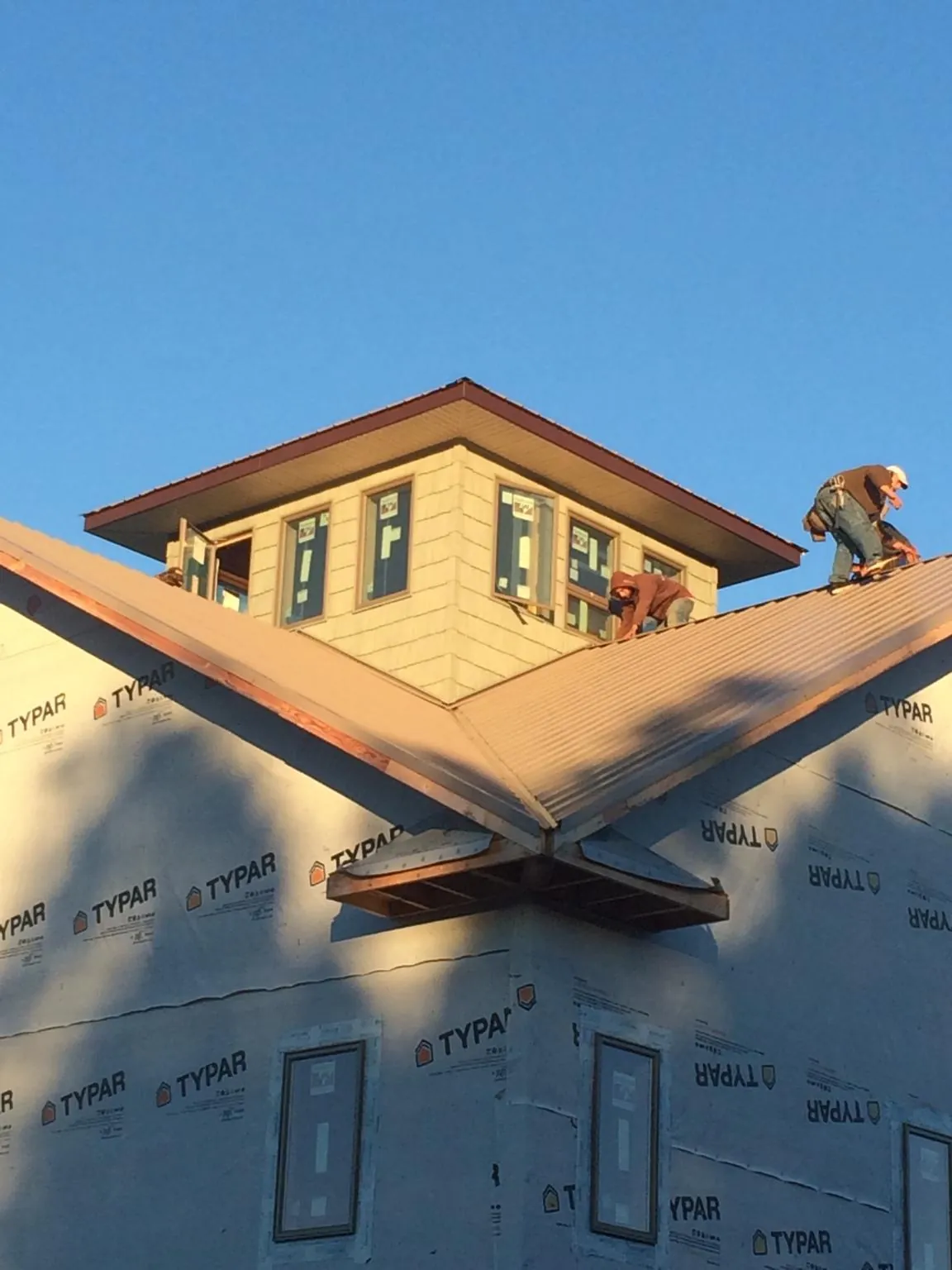 Roofers working around a rooftop cupola on a new metal roof at sunset — Roof Waterproofing in Joint Base Mdl by Roofing Brothers
